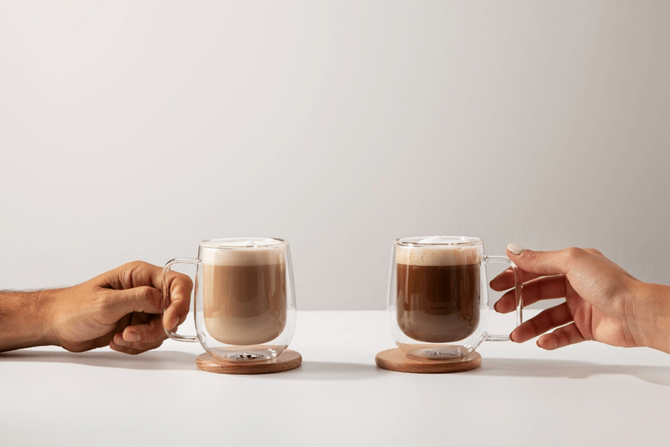 Two people drinking a cortado coffee and a latte. 