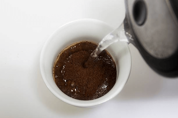 Adding cold water to coffee grounds to make cold brew